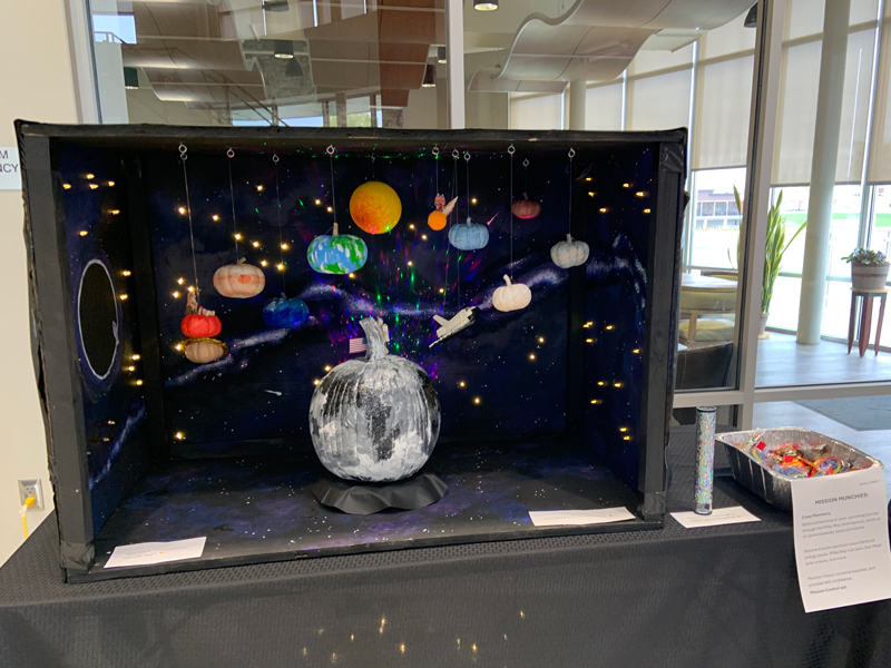 Solar system with pumpkin planets and a pumpkin decorated as the moon.